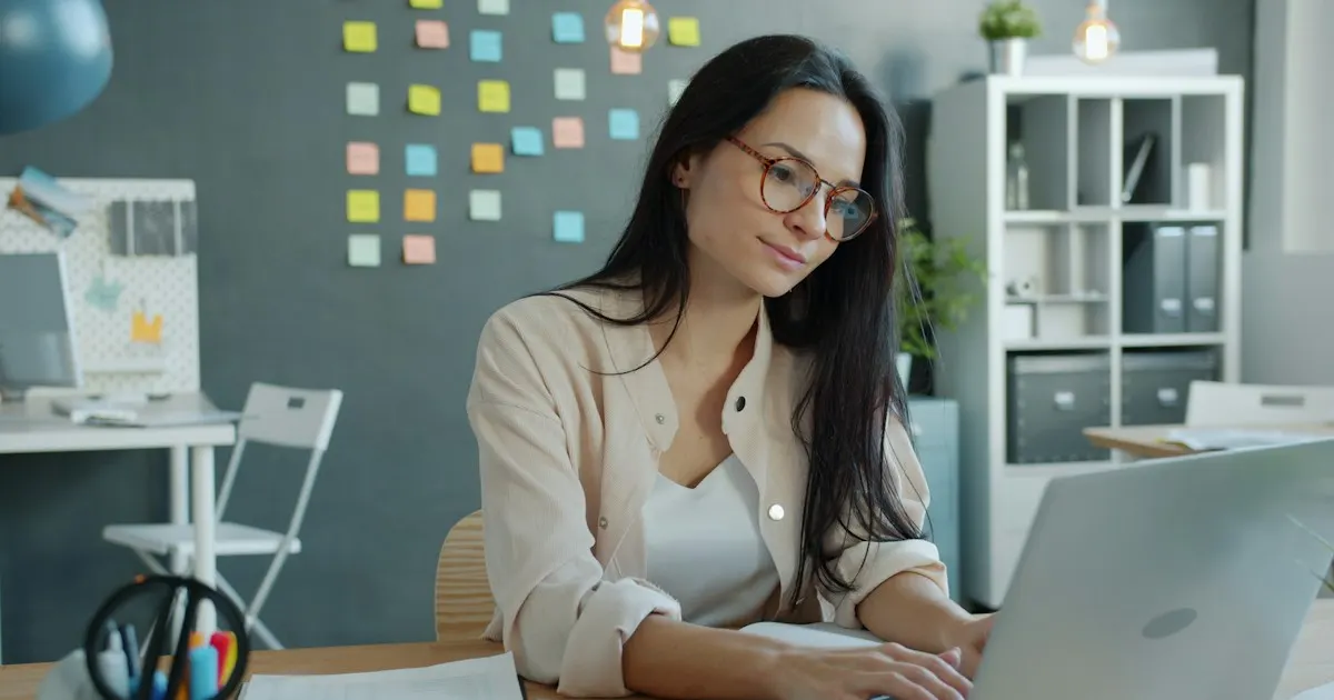 Woman wearing glasses working at a laptop in a modern office