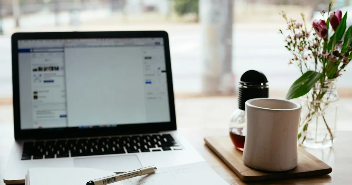 Laptop and open notebook on a desk for writing documentation